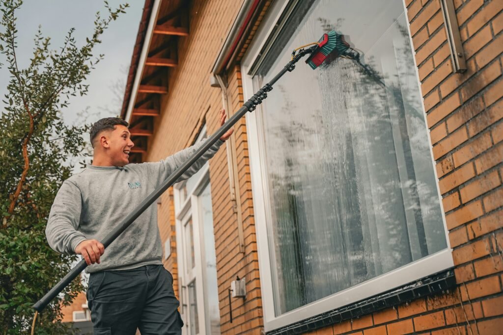 Fensterreinigung mit Teleskopstange und Wasserzufuhr an einer Hausfassade