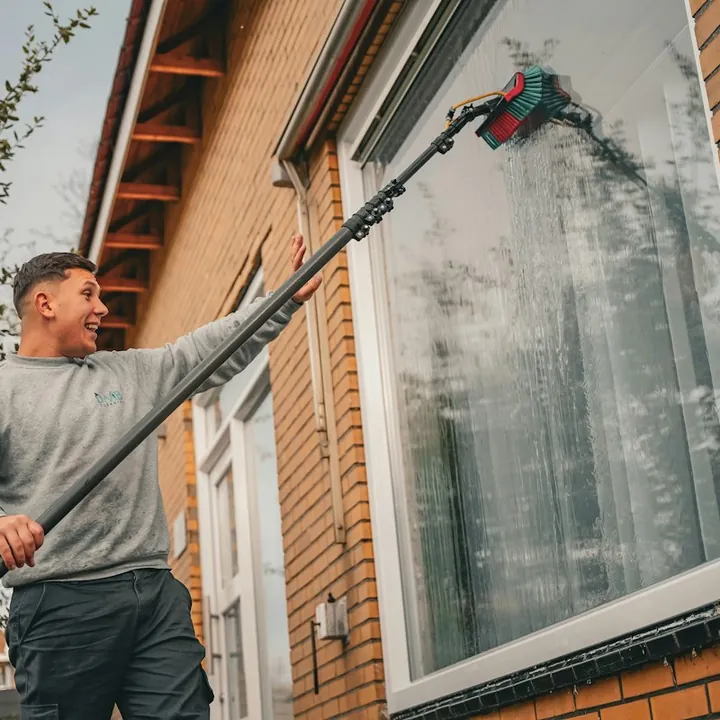 Fachmann reinigt Fenster von außen mit einer wasserführenden Teleskopstange