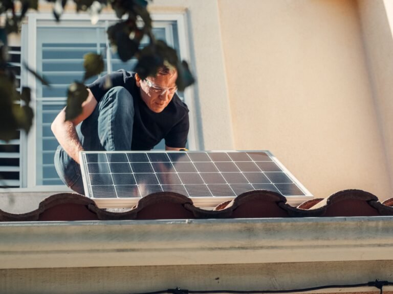 Mann montiert ein Solarmodul auf einem Ziegeldach