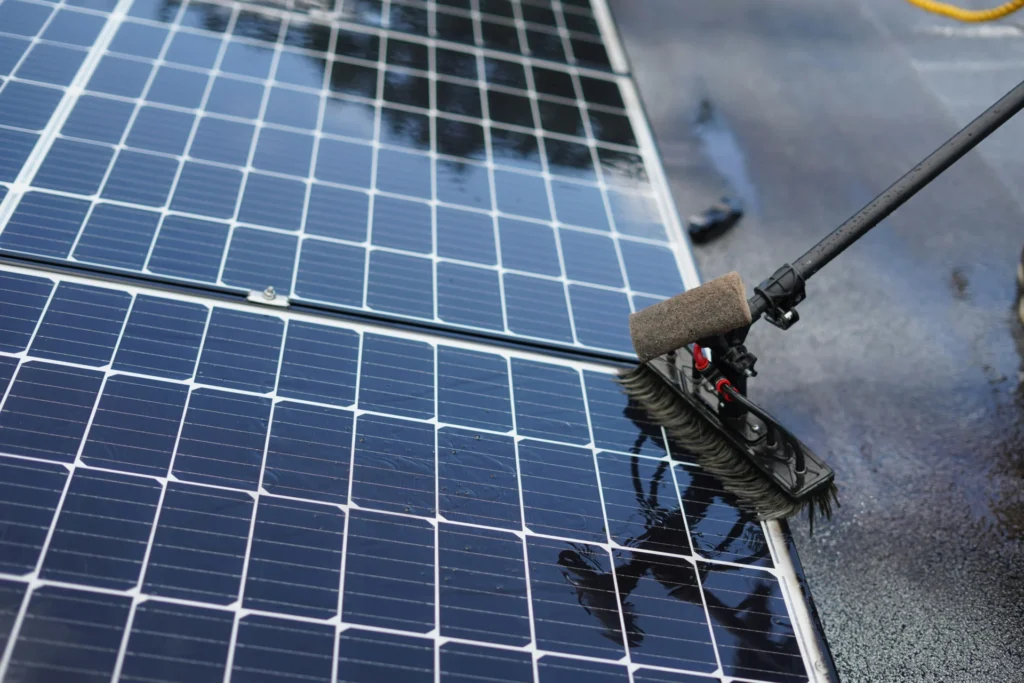 Solarmodule werden mit einer wasserführenden Bürste an der Teleskopstange gereinigt